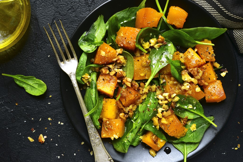 Roasted pumpkin salad with spinach and walnut .Top view.